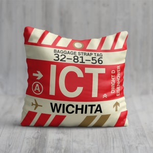 May include: A white and red pillow with a luggage tag design. The tag says "Baggage Strap Tag 32-81-56 ICT Wichita Dwight D Eisenhower".