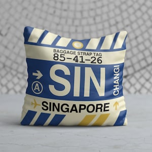 May include: Square pillow with a design resembling a baggage strap tag. The pillow features the letters "SIN" in large blue font, with "Singapore" below. The design includes blue and yellow stripes and the text "Changi".