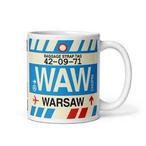Op de afbeelding: Witte keramische mok met een blauw en rood ontwerp van een luchthavenbagagelabel. Het label zegt "Baggage Strap Tag 42-09-71 WAW WARSAW" met een rood vliegtuigpictogram en de woorden "CHOPIN" verticaal gedrukt.