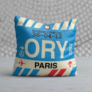 May include: Blue and white luggage tag with the text "ORY" and "PARIS" in white. The tag also has the text "BAGGAGE STRAP TAG 38-04-12" and "ORLY" in black.