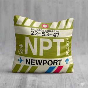 May include: A white and green luggage tag with the text "BAGGAGE STRAP TAG 22-53-47 NPT NEWPORT" and a red circle with a white arrow pointing to the right. The tag also has a red and blue stripe at the bottom and the word "PRIORITY" written vertically on the right side.