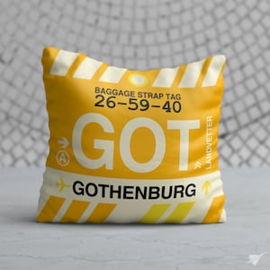 May include: Yellow and white cushion with a luggage tag design. The tag says "BAGGAGE STRAP TAG 26-59-40 GOT GOTHENBURG" with an arrow pointing to the right and a small aeroplane icon.