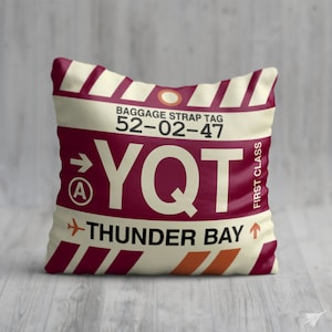 May include: A white and maroon luggage tag with the text "BAGGAGE STRAP TAG 52-02-47 YQT THUNDER BAY" and an airplane icon. The tag has a red circle with a white letter "A" inside.