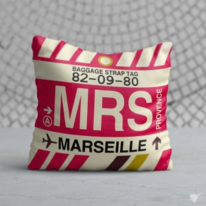 May include: A white and red pillow with a luggage tag design. The tag says "MRS" and "MARSEILLE" with the airport code "82-09-80" and "PROVENCE" printed on the side.