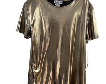 May include: Gold metallic short-sleeve top with a round neckline. The top is hanging on a black hanger. The tag on the shirt says "Cherry Hill".