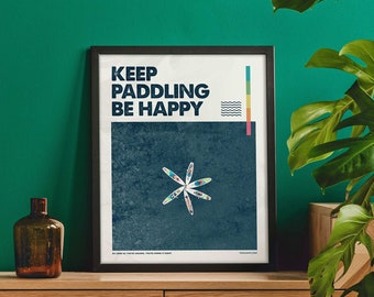 May include: A yellow armchair with wooden legs sits in front of a wooden cabinet with three drawers. A framed poster with the text "KEEP PADDLING BE HAPPY" hangs above the cabinet. A green wall is behind the furniture.