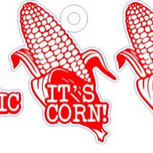 May include: Three red and white corn-shaped charms. One charm has the text "HAVE A CORNTASTIC DAY!", another says "IT'S CORN!", and the third is a corn graphic. Each charm has a small hole at the top for hanging.