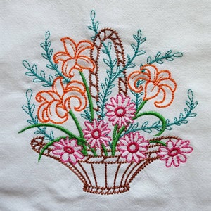 Puede incluir: Diseño bordado de una cesta llena de flores naranjas y rosas. La cesta es marrón y las flores están rodeadas de hojas verdes.