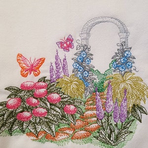 May include: Embroidered kitchen towel featuring a colorful garden scene with butterflies, flowers, and an archway. The design is stitched in shades of pink, purple, blue, green, and orange.