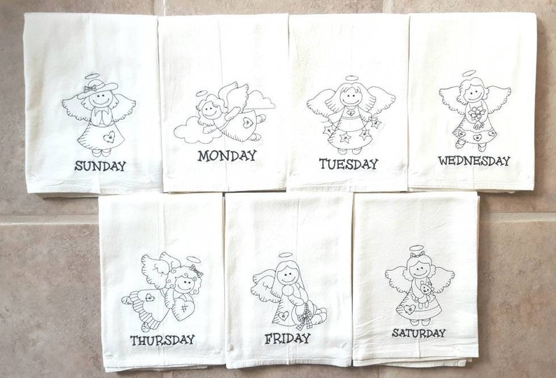 Pode incluir: Conjunto de sete panos de cozinha brancos, cada um bordado com um desenho de anjo diferente e o dia da semana em escrita preta. Os anjos t&ecirc;m asas, aur&eacute;olas e seguram v&aacute;rios objetos.