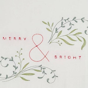 May include: Embroidered white kitchen towel with the text "Merry & Bright" in red thread and green leafy designs.