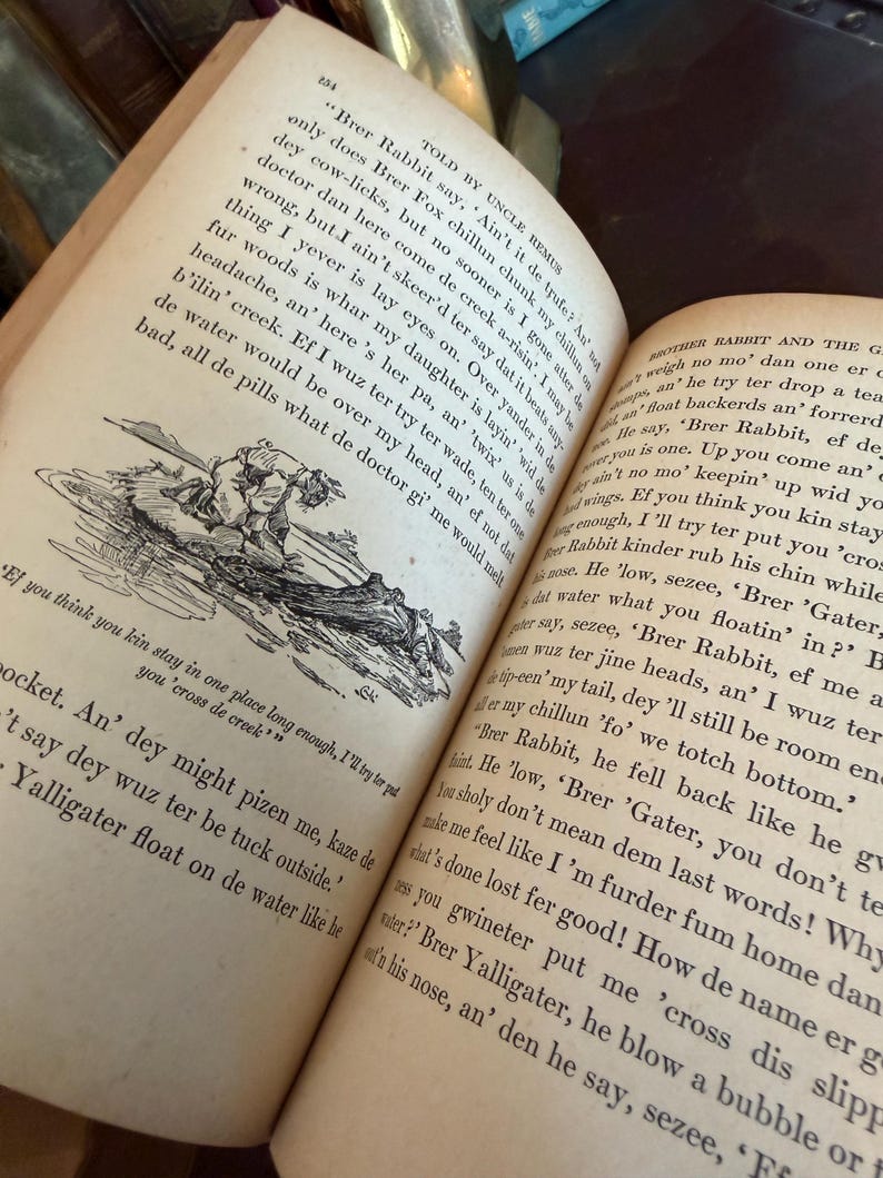 May include: Open book with aged, yellowed pages. Text and an illustration are visible. The book is open to a page with a drawing of a person in a boat. The text is in black ink.