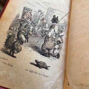May include: An open book with a vintage illustration featuring anthropomorphic animals in a detailed pen and ink style. The scene includes a fox, bear, and other creatures, with text reading "De King" and "sot right flat in a cheer."