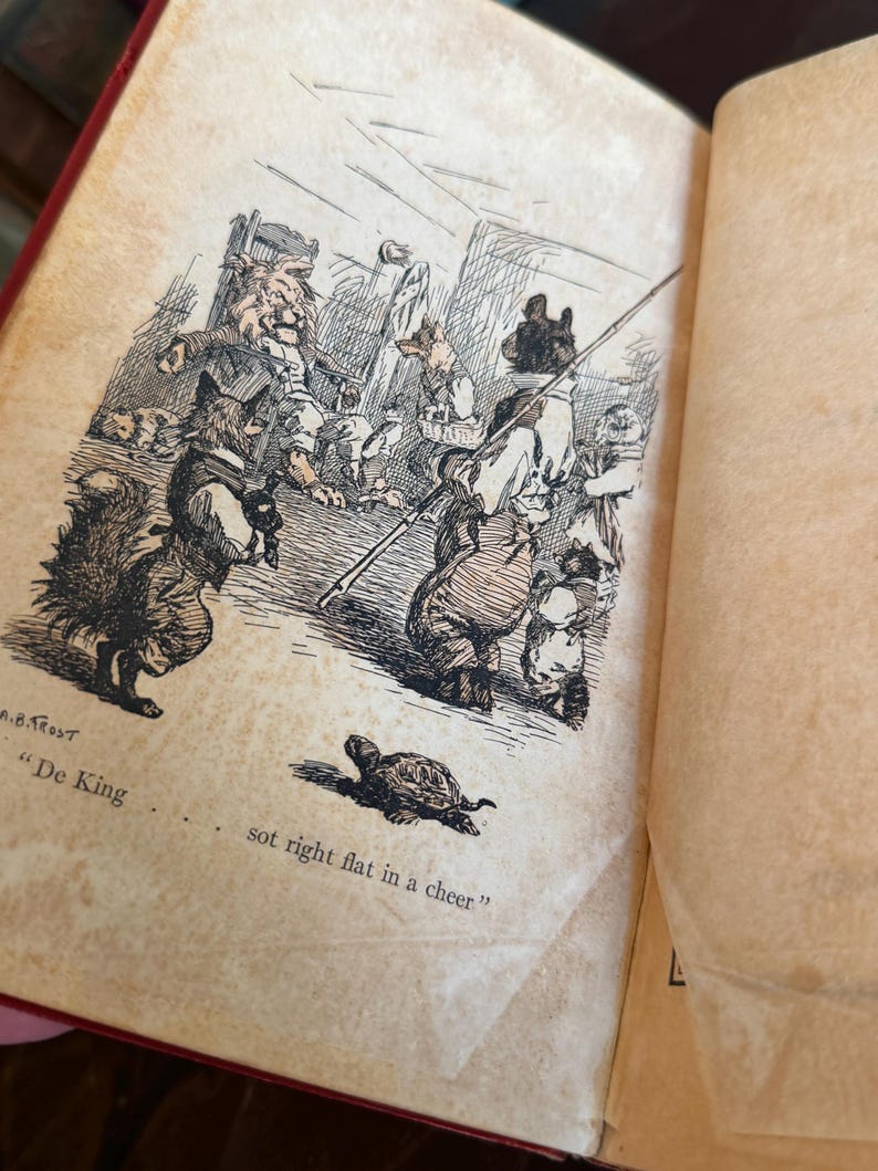 May include: An open book with a vintage illustration featuring anthropomorphic animals in a detailed pen and ink style. The scene includes a fox, bear, and other creatures, with text reading "De King" and "sot right flat in a cheer."