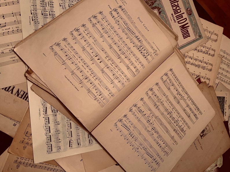 May include: A stack of vintage sheet music with the title "Don't Care" visible on the top sheet. The music is printed on cream-colored paper with black ink.