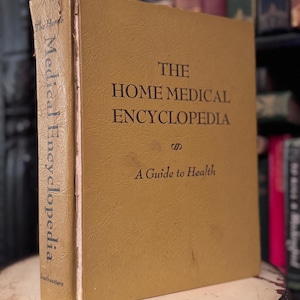 Peut inclure: Un livre ancien à couverture rigide intitulé "The Home Medical Encyclopedia: A Guide to Health". Le livre a une couverture de couleur moutarde avec des lettres noires. L'épine dorsale indique "Medical Encyclopedia" verticalement. Le livre est légèrement usé.