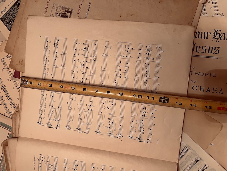 May include: A close-up of a sheet of music with musical notes printed on it. A measuring tape is placed across the sheet of music, with the numbers 1 through 16 visible. The text "Don't C" and "Our Ha Jesus" is visible on the page.