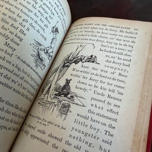May include: An open book with aged, yellowed pages. The text is in black ink, with illustrations of figures and scenes. The book is titled "Brother Rabbit and the Gizzard-Eater" and "Told by Uncle Remus". The book's binding is red.