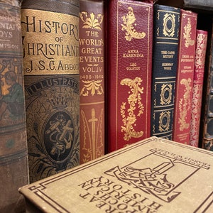 May include: A collection of vintage hardcover books with gold lettering and illustrations on the spines. The books include titles like "History of Christianity", "The World's Great Events", "Anna Karenina", and "The Caine Mutiny".