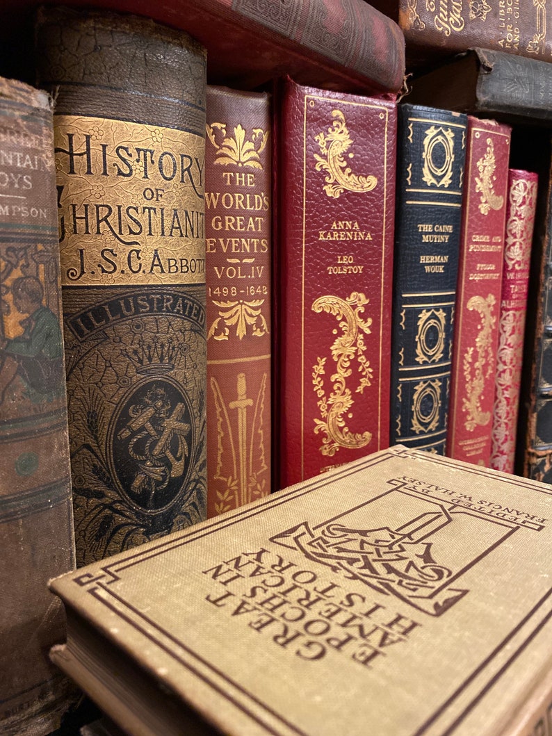 May include: A collection of vintage hardcover books with gold lettering and illustrations on the spines. The books include titles like "History of Christianity", "The World's Great Events", "Anna Karenina", and "The Caine Mutiny".