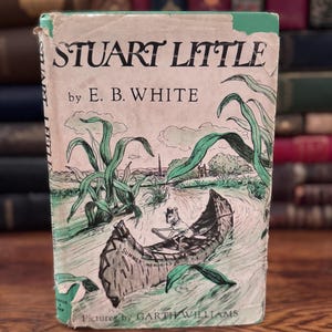 May include: Vintage hardcover book titled "Stuart Little" by E.B. White. The cover features an illustration of a mouse in a boat, with green and black accents. The book's cover also includes the text "Summer Memories" and "Pictures by Garth Williams."