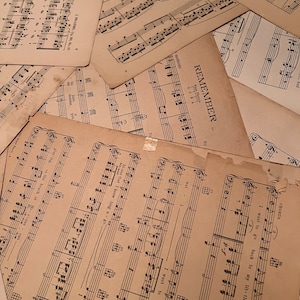 May include: A close-up of a stack of vintage sheet music with the title "Remember" visible. The music is printed on aged paper with black ink and includes musical notes and lyrics.