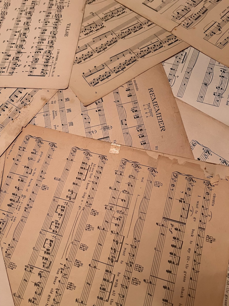 May include: A close-up of a stack of vintage sheet music with the title "Remember" visible. The music is printed on aged paper with black ink and includes musical notes and lyrics.