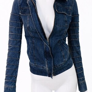 May include: A dark blue denim jacket with a zip-up front, collar, and pockets. The sleeves have a unique design with horizontal stitching. The jacket is displayed on a white mannequin.