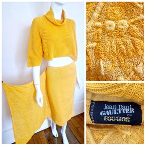 Könnte beinhalten: Ein gelber Strickpullover mit Rollkragen und ein passender gelber Rock. Der Rock hat einen langen, fließenden Schleier. Der Pullover und der Rock wurden beide von Jean Paul Gaultier für die Marke "Equator" hergestellt.