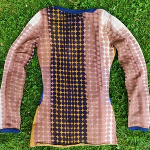 May include: A long-sleeved shirt with a brown and gold polka dot pattern. The shirt has a dark blue neckline and a vertical stripe of dark blue circles down the center.