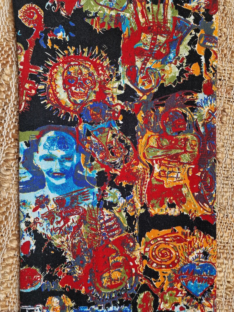 May include: A black fabric with a colorful, abstract pattern. The pattern features various shapes, lines, and figures in shades of red, blue, yellow, green, and orange.