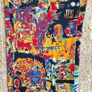 May include: Black fabric with a colorful, abstract print featuring faces, swirls, and the text "JPG".