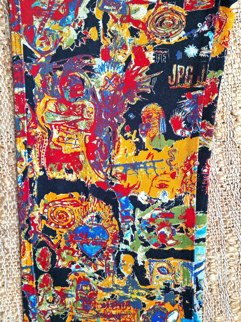 May include: Black fabric with a colorful, abstract print featuring faces, swirls, and the text "JPG".