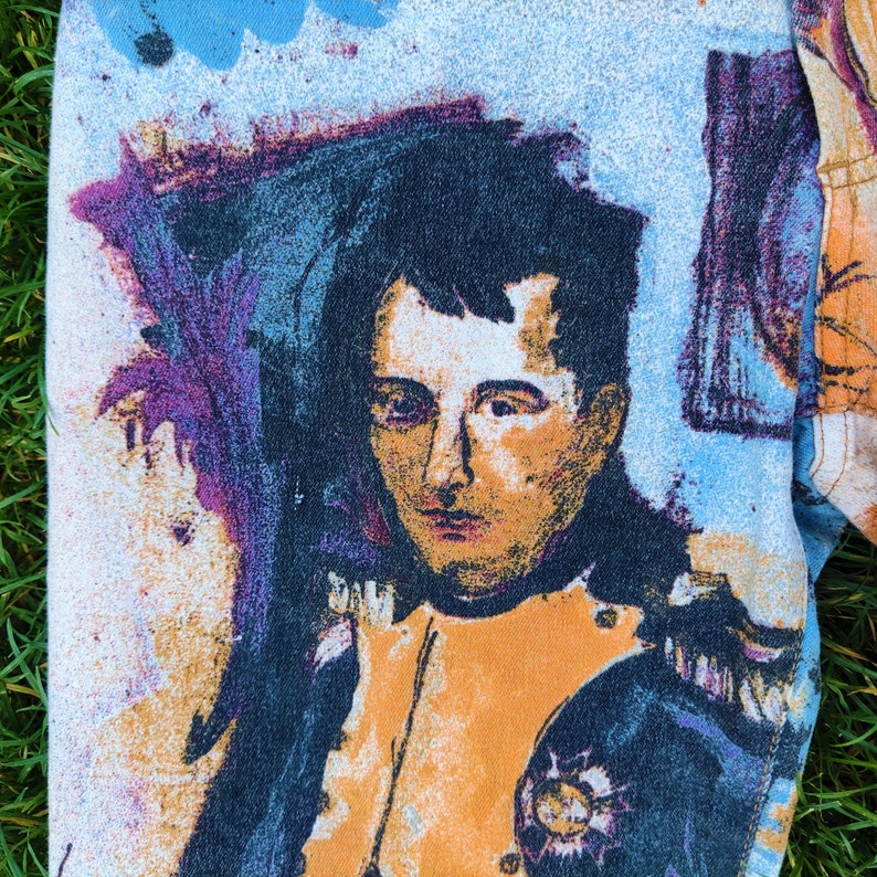 May include: A close-up of a colorful, abstract painting of a man's face. The man is wearing a dark blue and orange uniform with a gold trim. The background is a light blue and white.