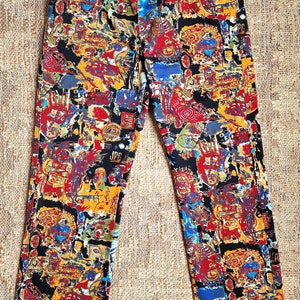 May include: Black pants with a colorful abstract print. The pants have a silver zipper and a silver belt buckle.