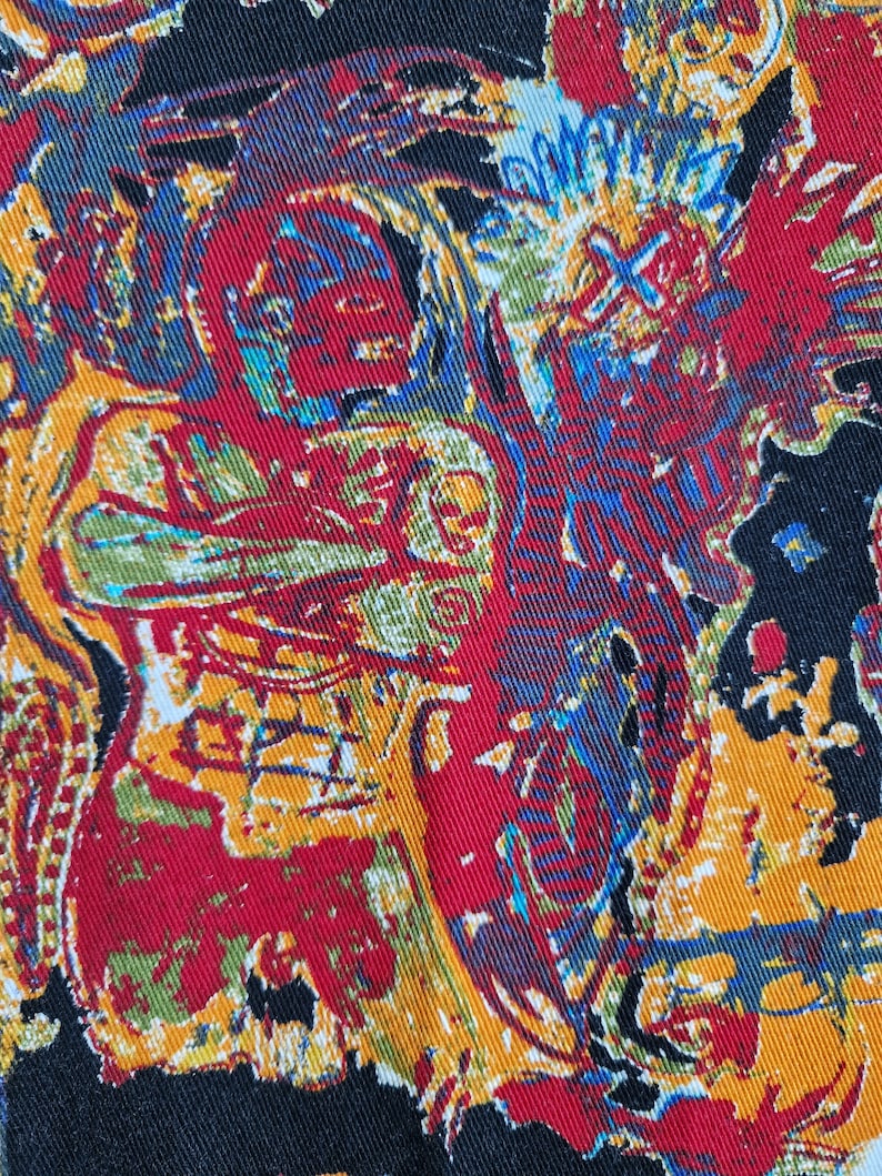 May include: A black fabric with a colorful abstract pattern. The pattern features red, yellow, blue, and green colors. The fabric has a textured surface.