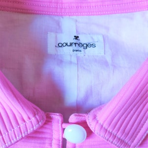 May include: A pink collared jacket with a white button and a white label that reads "Courr&egrave;ges Paris".