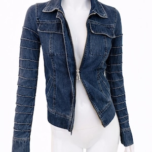 May include: A dark blue denim jacket with a zip-up front, two chest pockets, and decorative stitching on the sleeves. The jacket is displayed on a white mannequin.