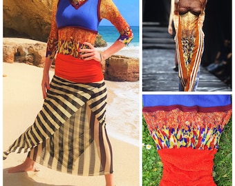 May include: A woman wearing a multi-colored striped skirt with a blue, red, and yellow top. The skirt is made of a sheer fabric and has a black and white striped pattern. The top is a cropped tank top with a blue base and a red and yellow floral pattern. The woman is standing on a beach with the ocean in the background.
