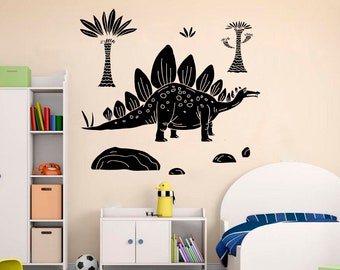 May include: Black and white dinosaur wall decal with a spiky back and a long tail. The decal is shown on a wall with a white bookcase and a white bed with blue and white striped bedding.