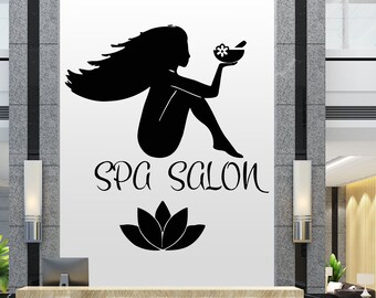 May include: Black and white silhouette of a woman holding a bowl with a flower inside. The text "SPA SALON" is below the woman, and a black lotus flower is below the text.