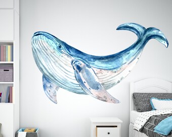 May include: A watercolor illustration of a blue whale swimming. The whale is depicted in shades of blue and white, with a detailed rendering of its body and fins. The artwork is likely a wall decal or print, suitable for a child's room.