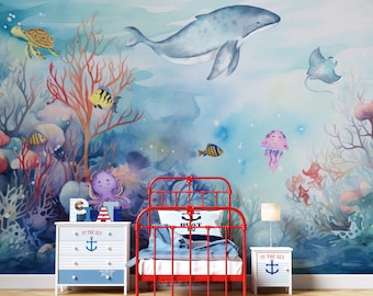 May include: A watercolour mural depicting an underwater scene with a whale, coral, fish, a turtle, a stingray, and a jellyfish. The mural is in a child's bedroom with a red metal bed frame and two white bedside tables with the text "At the Sea" and an anchor.