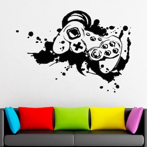May include: Black and white illustration of a video game controller with splattered paint in the background. The controller is stylised and has a simple design.