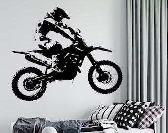 Peut inclure: Silhouette noire et blanche d'un pilote de motocross sautant sur une moto tout-terrain. Le pilote porte un casque et des lunettes. La moto a deux roues et un gros moteur.