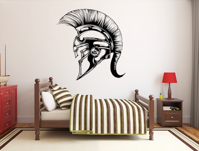 May include: A black and white illustration of a Roman helmet with a plume on top. The helmet is on a white wall above a wooden bed with a striped comforter.