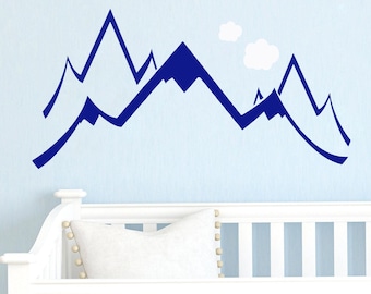 May include: Blue mountain silhouette wall decal with a white cloud design. The decal is applied to a white crib with a white pillow.