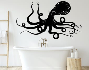 Könnte beinhalten: Schwarz-weiße Silhouette eines Kraken mit acht Tentakeln, die an einer weißen Wand über einer weißen Badewanne angebracht ist. Der Krake befindet sich in einem Badezimmer mit einem Holzhocker und einem Wasserhahn.