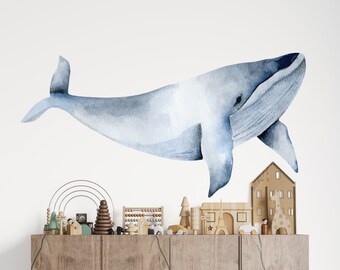 May include: A watercolor illustration of a blue whale on a white background. The whale is facing the right side of the image and is swimming upwards. The whale is a popular design for children's rooms and nurseries.
