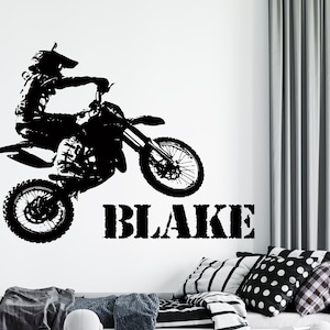 May include: Black and white silhouette of a motocross rider jumping a dirt bike with the name "BLAKE" printed below.